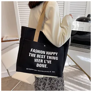 Detail of large black canvas tote bag with fashion text and silver metal snap button