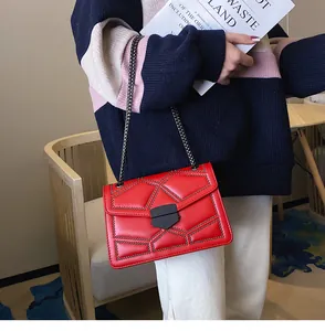 Détail d'un sac à bandoulière en cuir rouge matelassé avec clous noirs porté par un modèle