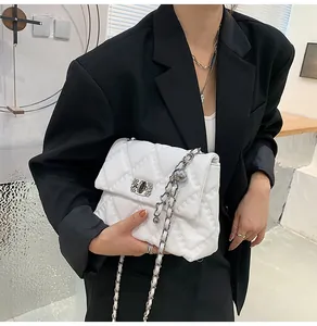Detail of white quilted chain bag featuring silver twist lock on a black blazer