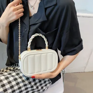 White quilted box bag with gold chain strap and woven top handle shown on fashion model