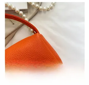 Détail de couture sur sac à main en cuir grainé orange vif avec texture litchi