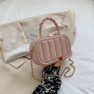 Pink quilted structured handbag with golden chain strap and top handle shown in a lifestyle view