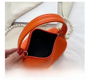 Détail de l'intérieur du sac en cuir grainé orange avec fermeture éclair dorée et perle