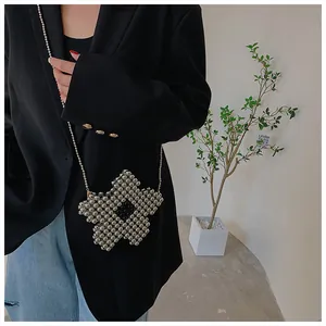 Detail of silver beaded flower crossbody bag featuring a fine metal chain strap