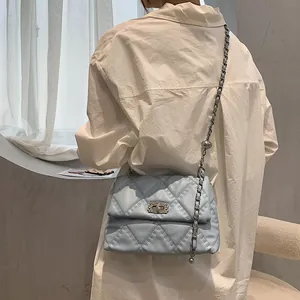 Quilted light blue shoulder bag with silver chain strap worn by a model in a minimalist room