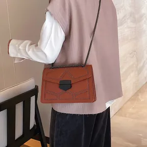 Sac bandoulière marron en cuir avec rivets et chaîne métallique sur mannequin