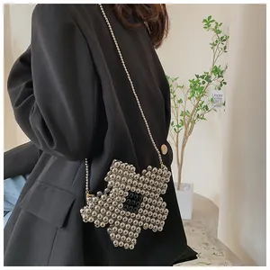 Detail of silver beaded flower crossbody bag worn on a black blazer with thin ball chain