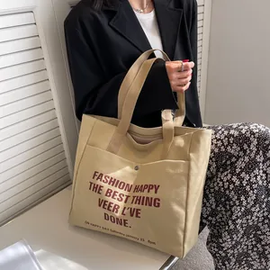 Large khaki canvas tote bag with red graphic lettering and front metal snap pocket