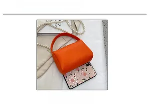 Mini sac à main en cuir grainé orange présenté avec un smartphone pour l'échelle