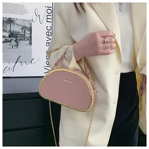 Detail van roze halfronde handtas met gouden metalen frame en kettingriem op een model