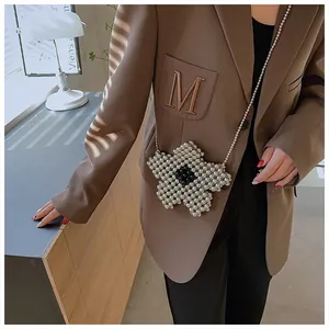 Detail of floral pearl woven crossbody bag with delicate chain on a brown blazer