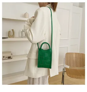 Fashionable bright green woven leather crossbody bag styled with a beige blazer
