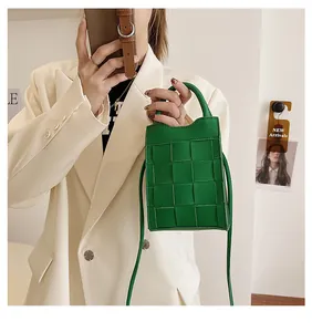 Close-up of green woven handbag paired with a minimalist cream blazer for a chic summer look