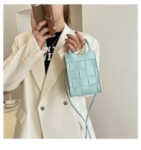 Detail of mint green woven crossbody mini bag with handle and detachable shoulder strap