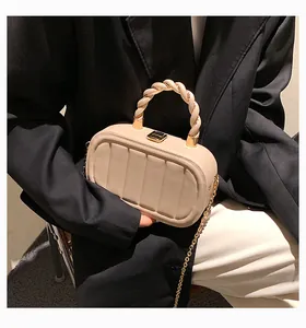 Detail showing cream crossbody bag with vertical stitching and spiral handle