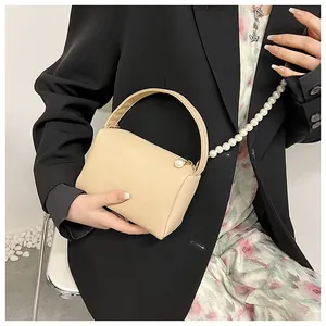Détail du sac à main en cuir grainé abricot avec chaîne en perles et bandoulière femme