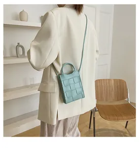 Detailed view of mint green woven crossbody bag styled in a minimalist interior