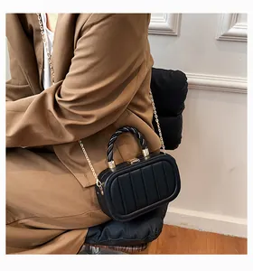 Detail of a black crossbody bag featuring vertical quilting and a braided handle with chain