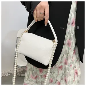 Détail du sac à main blanc en cuir grainé avec une élégante bandoulière en chaîne de perles