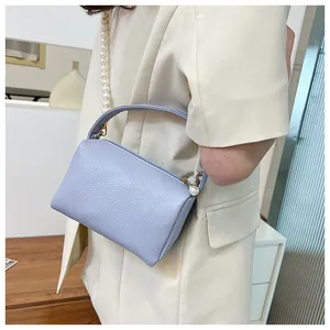 Détail du cuir grainé lavande et de la chaîne de perles sur la poignée du sac