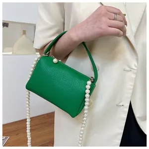 Détail du sac à main vert en cuir grainé avec chaîne décorative en perles blanches