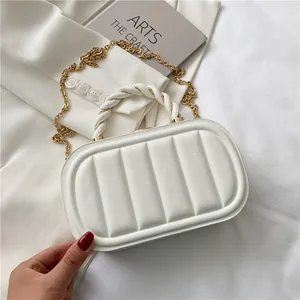 Elegant white quilted handbag with gold chain strap and braided handle on minimalist background