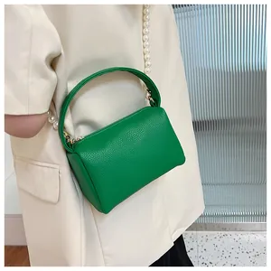 Détail du sac à main vert avec texture de cuir litchi et bandoulière en perles élégante