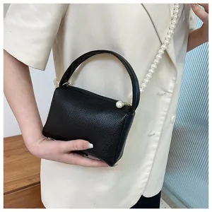 Détail du mini sac bandoulière noir avec texture litchi et élégante chaîne de perles