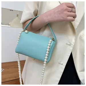 Détail du sac à main bleu Tiffany en cuir grainé avec une chaîne de perles décorative