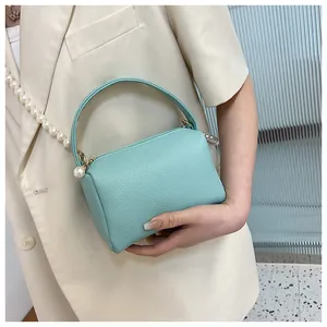 Détail du mini sac vert menthe en cuir grainé avec une élégante bandoulière en perles