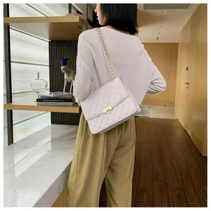 Sac à bandoulière matelassé blanc avec chaîne dorée porté par un mannequin