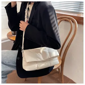 Detalle de bolso bandolera blanco acolchado con costuras grandes y correa ajustable de piel