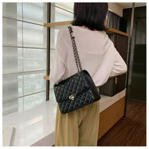Mannequin portant un grand sac cabas matelassé noir avec bandoulière chaîne dorée chic
