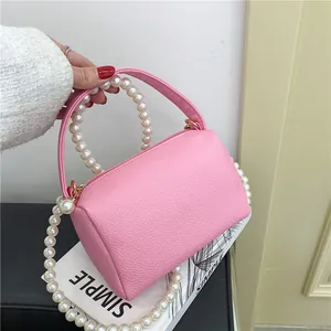 Sac à main cylindrique rose à texture litchi avec poignée en perles et bandoulière