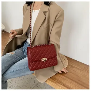 Détail du sac bandoulière matelassé bordeaux avec chaîne dorée sur un mannequin