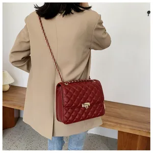 Détail du sac cabas matelassé bordeaux avec chaîne dorée et fermoir pivotant en métal