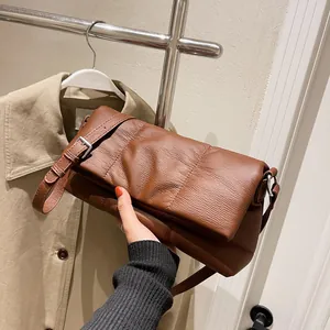 Bolso de hombro marrón en cuero suave con textura plisada y correa ajustable