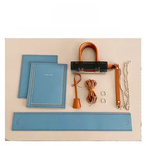 Flat lay of DIY leather tote kit including blue pieces, handles, chain, and sewing threads