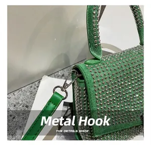Detailaufnahme von Silberhaken und grünem Lederriemen mit Metallnieten an der Handtasche