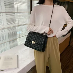 Sac fourre-tout noir matelassé avec chaîne dorée porté par un mannequin dans un cadre moderne