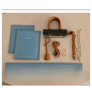 Flat lay of DIY light blue leather tote kit with straps, hardware and sewing threads