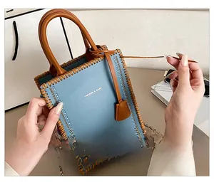 Detail of DIY handmade blue leather tote bag showing woven brown edges and metal chain