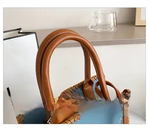 Detail showing the brown round handles and blue leather texture with woven edge trim