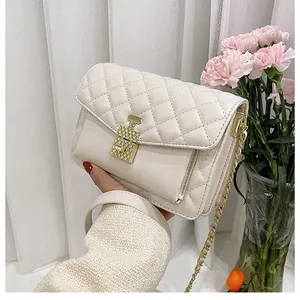 Detail of white quilted crossbody bag with luxury gold perfume bottle clasp and chain strap