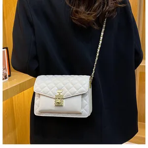 Detail view of a beige quilted crossbody bag with unique gold perfume bottle clasp