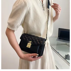 Detailed view of black quilted crossbody bag with gold perfume bottle lock and chain strap