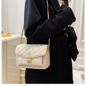 Close-up of beige quilted crossbody bag with unique gold perfume bottle lock and chain