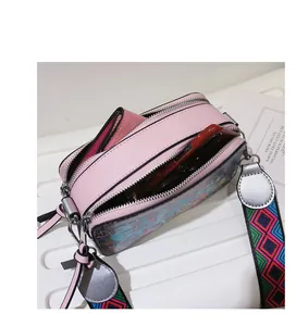 Detail view of pink graffiti camera bag featuring double zippers and wide woven strap