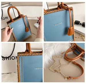 Detailed view of woven leather edges, metal rivets, and gold lettering on a blue tote bag