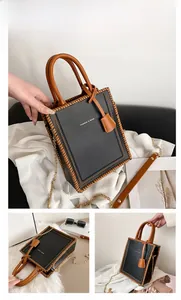 Detail of black leather tote bag with brown woven edges and elegant metal chain strap